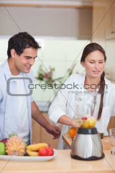 Portrait of a young couple making fresh fruits juice