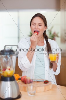 Portrait of a cute woman eating a fresh strawberry
