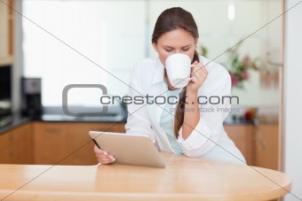 Woman using a tablet computer while drinking coffee