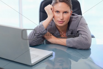 Serious businesswoman leaning on her desk