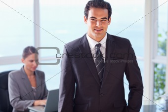 Smiling businessman with colleague behind him