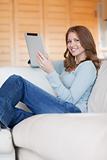Smiling woman with tablet relaxing on sofa