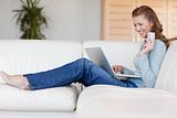 Happy woman booking flight online on the sofa