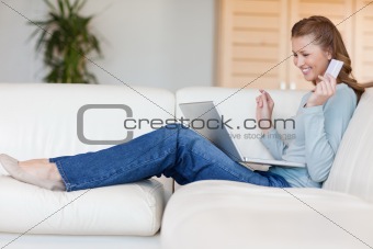 Young female on the sofa won an online auction