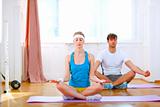 Young man and fit woman doing yoga at home
