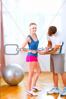 Personal trainer measuring belly of girl in sportswear

