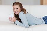 Young female enjoying a coffee break on her sofa