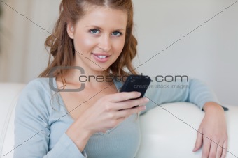 Woman on the couch typing on her smartphone