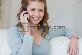Smiling female on the sofa talking on the phone