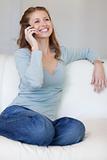 Smiling woman on the sofa answering the phone