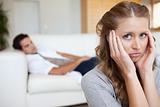 Woman suffering from headache with man on the sofa behind her