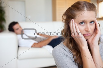 Woman suffering from headache with man on the sofa behind her