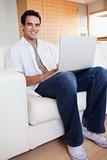 Smiling male with laptop on the sofa
