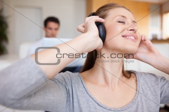 Woman enjoying music with man sitting behind her on the sofa