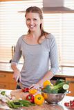 Smiling woman cutting ingredients for salad