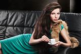 young elegant girl in green with cup, she looks  in to the lens