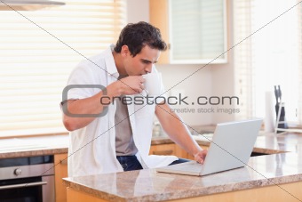 Man with coffee and laptop in the kitchen
