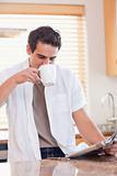 Man drinking some coffee while reading the newspaper