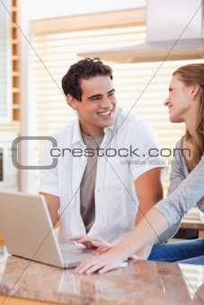 Smiling couple with laptop in the kitchen