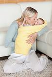 Mom kissing her baby that is wrapped into a cover