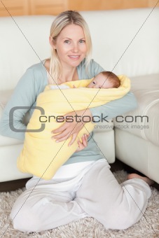 Mother holding her baby that is wrapped into a cover