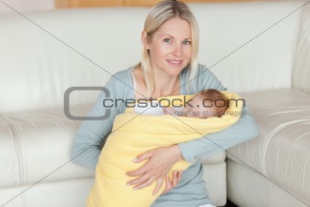 Mother sitting on the floor with her baby in her arms