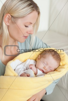 Mother holding her sleeping baby that is wrapped up in a cover