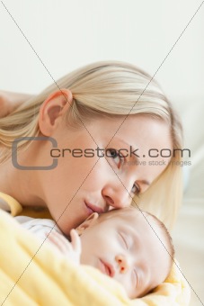 Lovely mother kissing her sleeping baby
