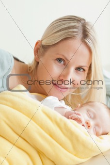 Young mother relaxing next to her sleeping baby