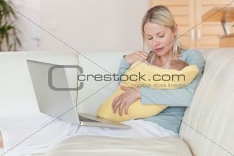 Mother with notebook on the sofa holding her baby