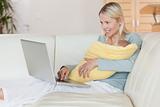 Mother with laptop on the couch holding her baby