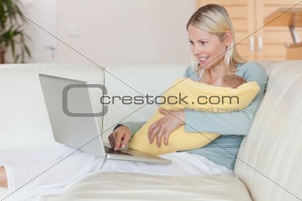 Mother with laptop on the couch holding her baby