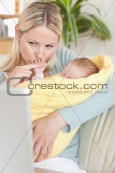 Mother kissing her baby's hand while looking at the laptop