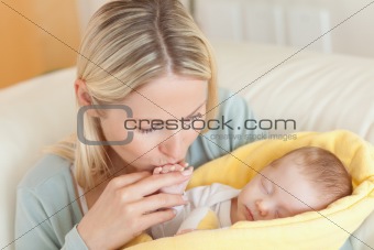 Mother on the sofa kissing her baby's hand