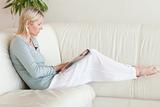 Side view of woman looking at catalog on the sofa 