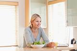 Female with salad and laptop in the kitchen having a glass of orange juice