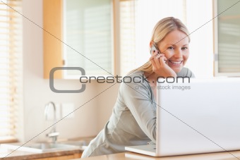 Smiling woman on the phone looking at her laptop