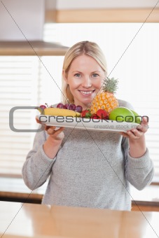 Woman presenting plate of fruits