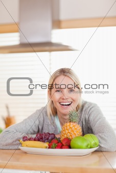 Laughing woman sitting behind plate of fruits