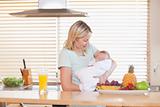 Woman holding her sleeping baby in the kitchen