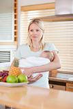 Woman standing in the kitchen with her baby on her arms