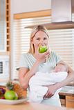 Mother with newborn on her arms having an apple