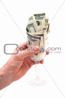 Hand holding glass filled with dollar bills