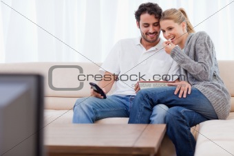 Charming couple watching TV while eating popcorn