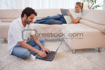 Woman using a tablet computer while her husband is using a laptop