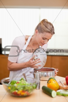 Portrait of a woman smelling in a sauce pan