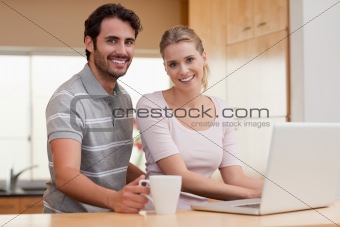 Smiling couple using a notebook while having coffee