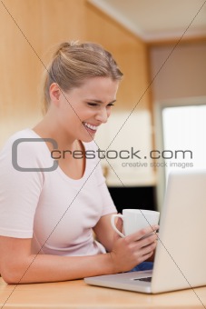 Portrait of a woman using a laptop while drinking a cup of a tea