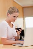Portrait of a woman using a laptop while drinking wine