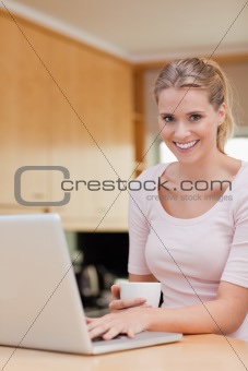 Portrait of a woman using a laptop while drinking coffee